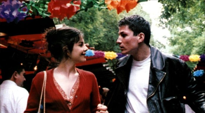 Rendez-vous in Paris A woman in a red cardigan and a man in a black leather jacket walk hand in hand at an outdoor Paris market decorated with colorful paper flowers, smiling at each other amidst the greenery and lively crowd, enjoying their rendez-vous.
