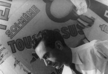 GALLERIES A man in a white shirt and tie stands in front of torn, overlapping posters with large French text. He looks downward in profile, lit from the left. The background includes bold letters and partial words in various fonts and sizes. The image is black and white.