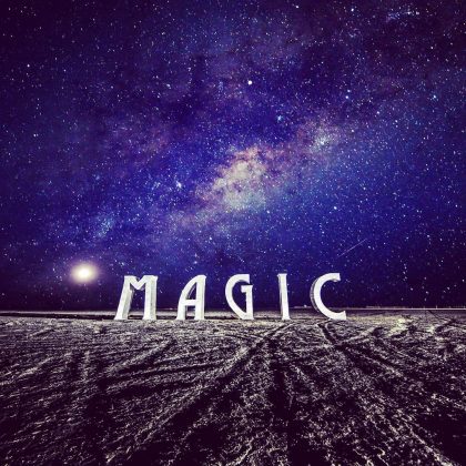 Large white letters spelling “MAGIC” stand on a barren, textured landscape at night under a vivid, star-filled sky with the Milky Way above—an iconic scene among BurningMan photos or what some might call photos impossibles.
