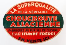 Choucroute-Sauerkraut An oval vintage sign in red, green, and beige reads La Superqualité de la véritable Choucroute Alsacienne, celebrating authentic Sauerkraut. Bold, decorative text dominates the design and highlights its artisanal quality.