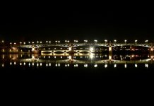 Guide du visiteur de la ville de Toulouse Le pont Saint-Pierre illuminé enjambant la Garonne au crépuscule, avec le dôme en cuivre emblématique de l'Hôpital de La Grave se reflétant dans l'eau.