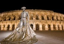 Visitors Guide to the City of Nîmes Bullfighter statue in front of Nîmes Arena at night