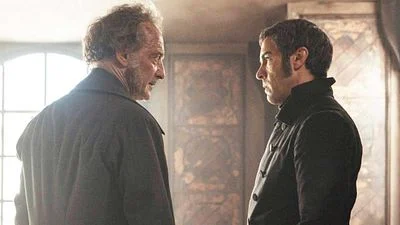 A tense profile shot from the 2026 film Les Misérables, featuring Vincent Lindon as Jean Valjean facing a stern Tahar Rahim as Javert in 19th-century period clothing.